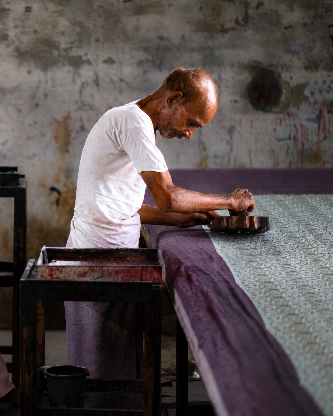 Artisan hand block printing fabric using carved wooden blocks in India.